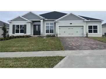 Gray two-story house with a three-car garage and landscaped lawn at 3271 Roseville Dr, Apopka, FL 32712