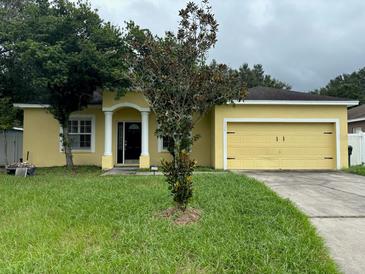 Charming yellow house with a two-car garage and a manicured lawn at 5320 Song Sparrow Ct, Lakeland, FL 33811