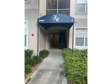Building entrance with stairs and landscaping at 3000 Laurel Park Ln # 104, Kissimmee, FL 34741