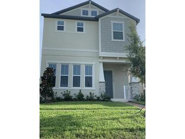 Two story home with light beige siding and a green lawn at 15102 Stuttgart Aly, Winter Garden, FL 34787