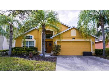 Two-story yellow house with palm trees and a two-car garage at 2508 Dharma Cir, Kissimmee, FL 34746