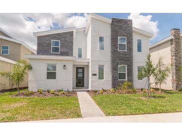 Two-story modern home with gray and white exterior and landscaping at 9102 Sommerset Hills Dr, Davenport, FL 33896