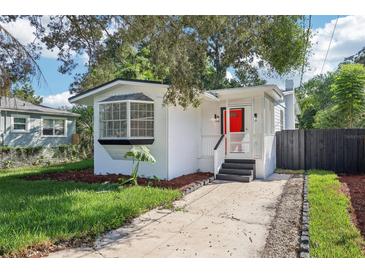 Adorable bungalow with a red door, freshly landscaped yard, and a paved driveway at 1815 Larkin Ave, Orlando, FL 32812