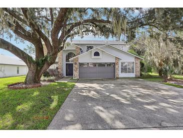 Two-story home with gray garage door and landscaping at 2291 E Riviera Blvd, Oviedo, FL 32765