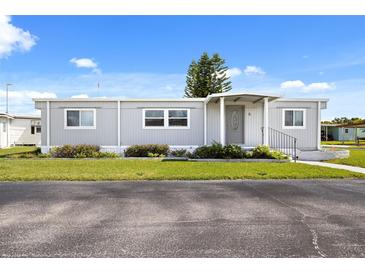 Gray single-wide manufactured home with a covered entryway and well-manicured lawn at 6 Orangewood Dr, Fruitland Park, FL 34731