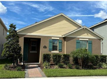 Two-story home with beige and brown siding, teal shutters, and a landscaped front yard at 16613 Point Rock Dr, Winter Garden, FL 34787