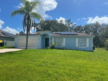 Light blue house with a two-car garage and solar panels at 733 Robin Ct, Kissimmee, FL 34759