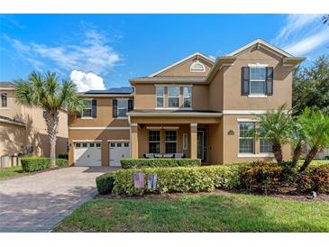 Two-story house with a two car garage, lush landscaping, and solar panels at 16328 Wind View Ln, Winter Garden, FL 34787