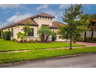 Single-story home with tile roof, landscaping, and paved driveway at 3951 Carrick Bend Dr, Kissimmee, FL 34746