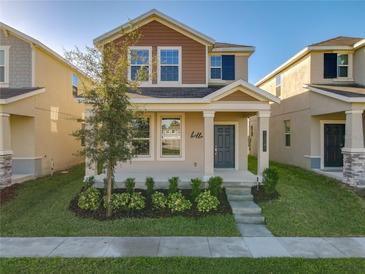 Two-story house with taupe and brown siding, landscaping, and a front porch at 13041 Inkwell Aly, Winter Garden, FL 34787