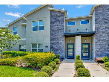 Modern two-story townhome with gray siding, stone accents, and blue doors at 740 Pebble Beach Dr, Davenport, FL 33896