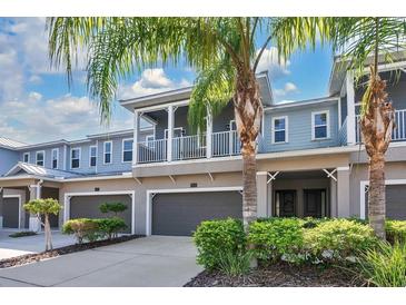 Two-story townhome with attached garage, balcony, and lush landscaping at 593 Lake Wildmere Cv, Longwood, FL 32750