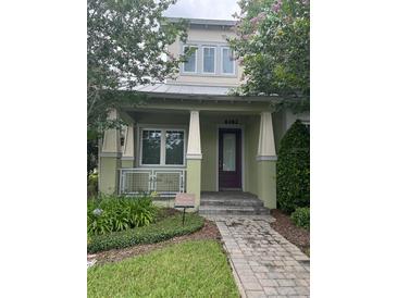 Green two-story home with a purple door and landscaped walkway at 8282 Tavistock Lakes Blvd, Orlando, FL 32827