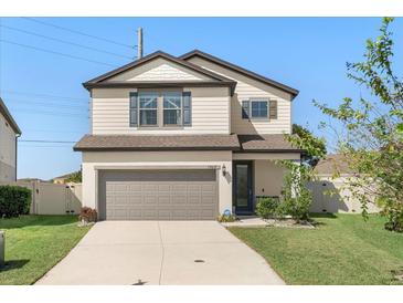 Two-story house with neutral siding, gray garage door, and manicured lawn at 1909 Cayman Cove Cir, St Cloud, FL 34772
