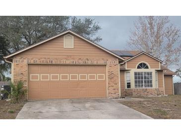 Tan house with a two-car garage and solar panels at 2618 Coventry Ln, Ocoee, FL 34761