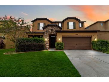 Two-story house with a brown garage door and lush green lawn at sunset at 5009 Torchwood Dr, Minneola, FL 34715