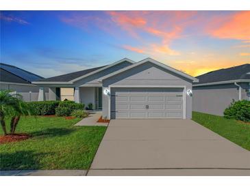One-story home with gray siding, two car garage and landscaped yard at 653 Persian Dr, Haines City, FL 33844