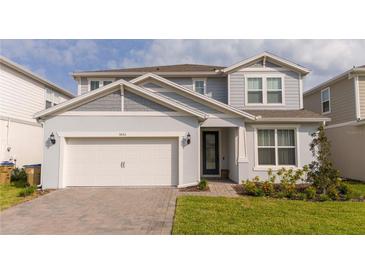 Two-story home with gray siding, white garage door, and landscaping at 5653 Oak Knoll Dr, St Cloud, FL 34771