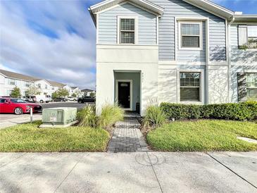 Two-story townhome with gray siding, a brick walkway, and landscaping at 8931 Sydney Ave, Kissimmee, FL 34747