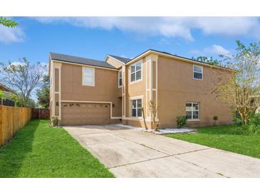 Tan two-story house with a two-car garage and landscaped lawn at 1344 Holly Glen Run, Apopka, FL 32703