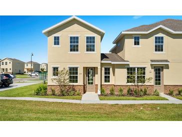 Two story townhome with tan siding, stone accents, and landscaping at 164 Holly Village Dr, Davenport, FL 33837