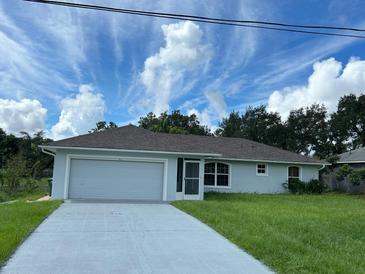 House exterior featuring a gray garage door, light blue paint, and a neatly trimmed lawn at 2421 Omaha Dr, Deltona, FL 32738