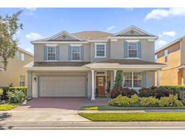 Two-story house with light beige siding, gray shutters, and a brick driveway at 621 Legacy Park Dr, Casselberry, FL 32707