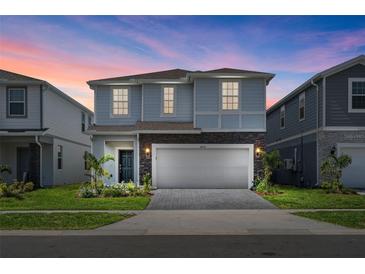 Two-story house with light gray siding, gray stone accents, and a two-car garage at 3955 Lana Ave, Davenport, FL 33897
