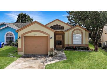 Tan house with a two-car garage and well-maintained lawn at 6525 Spring Land Ct, Orlando, FL 32818