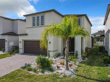 Two-story house with brown garage door, palm tree, and well-manicured lawn at 1130 Arisha Dr, Kissimmee, FL 34746