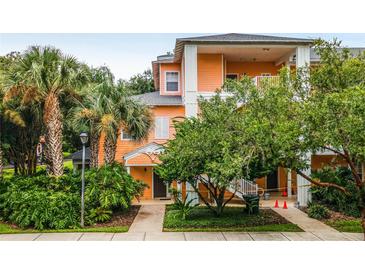 Two-story building with peach-colored facade, lush landscaping, and palm trees at 101 New Providence # 9101, Davenport, FL 33897