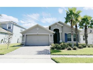 Single-story home with gray exterior, paver driveway, and lush landscaping at 3995 Scarlet Branch Rd, Orlando, FL 32824