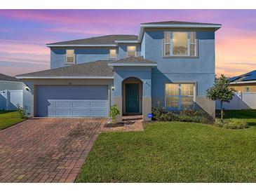 Two-story house with a gray exterior, brick driveway, and landscaped lawn at 911 Avenal, Davenport, FL 33837