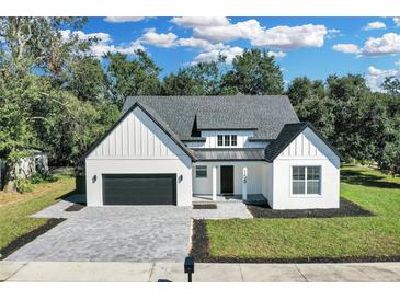 Modern farmhouse style home with a gray roof, white exterior, and a paved driveway at 155 Pearl St, Auburndale, FL 33823