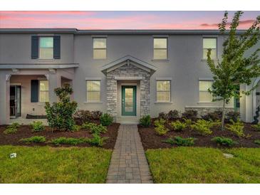 Two-story townhome with a stone accent and landscaped walkway at 11209 Listening Dr, Orlando, FL 32832