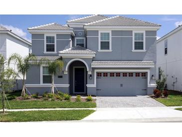 Two-story house with gray siding, three-car garage, and landscaping at 8843 Interlocking Ct, Davenport, FL 33896