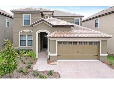 Two-story house with a large, attached garage and landscaped front yard at 1423 Thunderbird Rd, Davenport, FL 33896