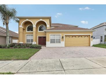 Two-story home with arched entryway and three car garage at 6526 Lake Pembroke Pl, Orlando, FL 32829