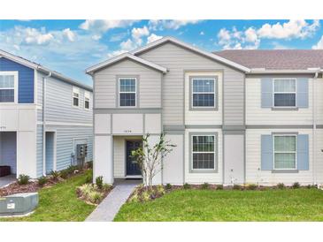 Two-story townhome with gray siding, shutters, and a landscaped front yard at 3894 Lana Ave, Davenport, FL 33897