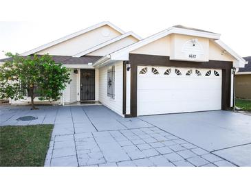 Front view of a single-story house with a two-car garage and landscaped yard at 6632 Meritmoor, Orlando, FL 32818