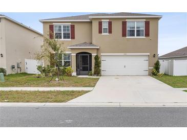 Two-story house with tan exterior, red shutters, and a two-car garage at 740 Squires Grove Dr, Winter Haven, FL 33880