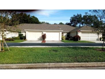 Exterior view of a light beige home with a two-car garage at 549 Juniper Way, Tavares, FL 32778