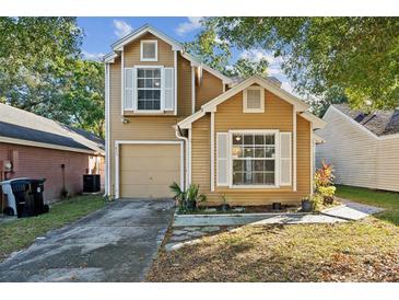 Tan two-story house with a garage and landscaping at 1845 Iroquois Dr, Apopka, FL 32703