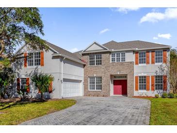 Two-story house with brick and stucco exterior, red door, and paver driveway at 3211 Eagle Watch Dr, Kissimmee, FL 34746