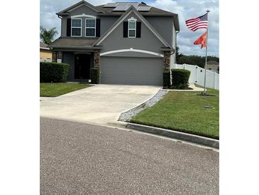 Two story house with gray siding, solar panels, and double car garage at 1952 Dunn Cove Dr, Apopka, FL 32703