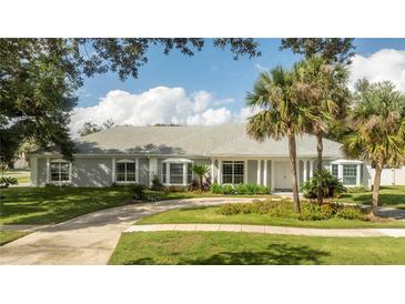 Gray house with white columns, landscaped yard, and circular driveway at 5646 Masters Blvd, Orlando, FL 32819
