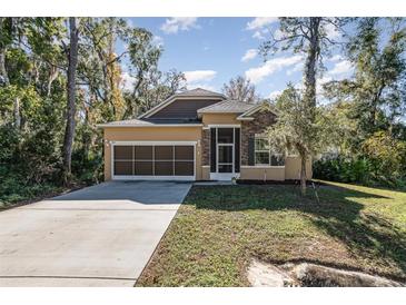Tan house with stone accents and a screened porch, two car garage, and landscaped yard at 1989 Marsh Hen Vlg, Deland, FL 32720
