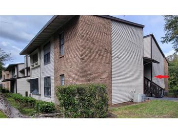 Condo building exterior with brick and siding, showcasing stairs and AC unit at 4641 Cason Cove Dr # 2124, Orlando, FL 32811