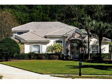 Two-story house with tile roof, stone accents, and lush landscaping at 943 Elm Harbor Ct, Lake Mary, FL 32746