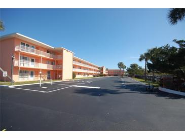 Exterior view of a light peach two-story condominium building with ample parking at 721 S Beach St # 217A, Daytona Beach, FL 32114